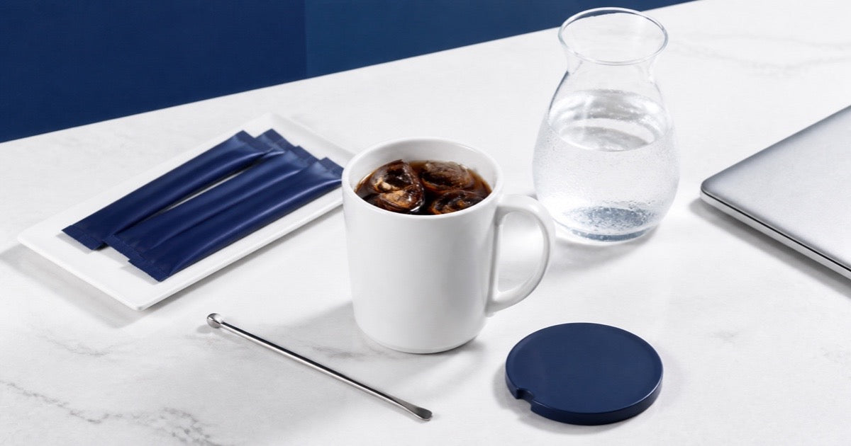 紺と白のオフィスデスクに置かれたアイスコーヒー、水、個包装コーヒーのイメージ